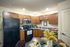 Modern kitchen with warm wooden cabinetry, sleek black appliances, and elegant dining setup perfect for stylish living.