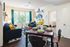 Inviting apartment living room with sleek hardwood floors, vibrant decor, and ample natural light from large windows. Cozy dining area set for a charming meal.