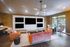 Modern lounge area with stylish orange seating, multiple flat-screen TVs, and large windows offering natural light.