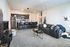 Contemporary open-plan living space featuring a cozy gray couch, chic kitchen with sleek appliances, and stylish bar seating.