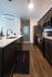 Modern kitchen with sleek dark cabinetry, stainless steel appliances, and stylish ring lighting, ideal for culinary creativity.