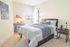 Bright and inviting bedroom with modern decor, a cozy bed, stylish desk, and ample natural light.