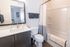 Modern bathroom with elegant fixtures, featuring a sleek vanity, large mirror, and cozy bath area.