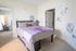 Charming bedroom with floral wall accents, cozy bed, and stylish decor, exuding comfort and elegance.