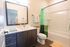 Modern bathroom featuring a sleek vanity, large framed mirror, and elegant shower area with a green curtain.