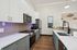 Modern kitchen with sleek stainless steel appliances, elegant white cabinets, and stylish wooden flooring.