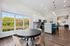Bright and airy open-plan kitchen and dining area with modern furnishings and a scenic window view of lush greenery.