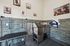 Modern pet grooming room with stylish tiled walls, stainless steel sink, grooming table, and playful dog artwork.