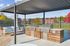 Inviting outdoor patio area with sleek grills under a modern pergola, perfect for entertaining amid picturesque fall colors.