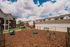Charming apartment complex with pet-friendly play area, featuring play structures and seating, under a vibrant blue sky.