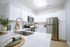 Bright and modern kitchen with sleek stainless steel appliances, elegant white cabinetry, and a cozy dining setup.