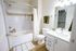 Bright and modern bathroom featuring a white bathtub, elegant sink vanity, and stylish fixtures, perfect for relaxation.