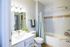 Bright and inviting bathroom featuring a modern vanity, sleek fixtures, and a relaxing bathtub with elegant tile accents.
