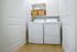 Modern laundry area with state-of-the-art washer and dryer, featuring sleek shelving filled with stylish baskets and jars.