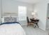 Charming bedroom with a cozy bed, elegant desk setup, and soft natural light through the window, perfect for relaxation and productivity.
