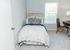 Inviting bedroom with chic decor, featuring a cozy bed, stylish patterned cushions, and a sunlit window, complemented by a sleek writing desk and chair.