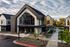 Modern commercial building with sleek architecture and large windows, surrounded by well-maintained landscaping and a spacious parking area.