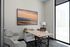 Modern home office with natural light, featuring a sleek desk, comfortable armchair, and mountain landscape artwork.