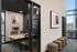 Modern office space featuring a sleek meeting room with elegant abstract art, floor-to-ceiling windows, and comfortable seating.