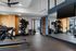 Modern, well-equipped gym with treadmills, exercise balls, and mirrored walls, offering a spacious and inviting workout area within the apartment complex.