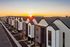 Modern row of townhouses with striking architectural design at sunset, featuring clean lines and a serene neighborhood setting.