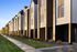 Modern townhomes bathed in golden sunlight, featuring sleek architecture and well-maintained landscaping along a quiet suburban street.