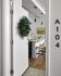 Inviting apartment entrance with a charming wreath on a white door leading to a stylish kitchen with modern bar stools and elegant pendant lighting.