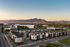 Charming residential community at sunset with modern townhouses, lush greenery, and stunning mountain backdrops.