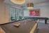 Chic recreation room with a pool table and shuffleboard, featuring modern decor and large windows overlooking lush greenery.