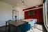 Modern conference room with sleek wooden table, blue chairs, a large wall-mounted TV, and artistic light bulb decor, creating a stylish and functional workspace.