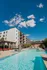 Inviting apartment complex with a stunning outdoor pool, surrounded by modern architecture and vibrant landscaping under a sunny blue sky.