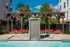 Luxurious outdoor area featuring a modern pool with cascading waterfall, stylish red lounge chairs, and a pergola for relaxation.