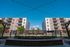 Chic apartment complex showcasing modern architecture, inviting balconies, and vibrant landscaping under a clear blue sky. The warm outdoor firepit adds a touch of luxury, perfect for relaxing evenings.