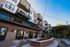 Chic apartment complex exterior with modern balconies, inviting outdoor seating area, and cozy fire pit under string lights.