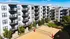 Modern apartment complex with private balconies and a vibrant outdoor sand volleyball court, perfect for active lifestyles.