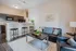 Chic open-plan living area with a modern kitchen, sleek bar stools, and cozy seating arrangement. Bright and inviting atmosphere with stylish decor and ample space.