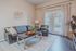 Inviting living room with modern leather seating, elegant decor, and bright natural light through glass doors leading to a serene outdoor view.