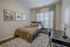 Inviting bedroom with a comfortable bed, elegant decor, and natural light streaming through window blinds.