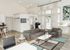 Bright and modern communal area featuring sleek gray sofas, a stylish white coffee table, and contemporary decor with large windows enhancing natural light.