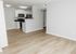 Modern open-plan living area with sleek kitchen, bright lighting, and elegant wood flooring.
