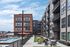 Modern urban apartment complex with stylish outdoor seating, inviting pool, and chic balconies under a bright blue sky.