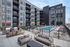 Modern apartment complex with inviting outdoor patio, relaxing lounge chairs, colorful umbrellas, and a sparkling pool, perfect for social gatherings and leisure.