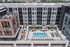 Modern apartment complex with a vibrant rooftop pool, lounge chairs, and stylish outdoor seating area featuring bright orange umbrellas.
