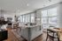 Bright and modern open-concept living space with a stylish kitchen, cozy gray sofa, and large windows offering abundant natural light.