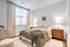 Cozy and inviting bedroom with elegant wooden furniture, soft lighting, and a stylishly draped bedspread in a well-lit serene space.