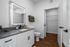 Modern bathroom featuring elegant wooden flooring, a sleek vanity with illuminated mirror, and spacious closet access.