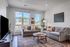 Bright and inviting living room featuring modern gray sofas, a stylish wooden coffee table, and large windows with picturesque views.