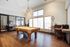 Elegant entertainment room with modern pool table, sleek bar stools, and a cozy meeting space, filled with natural light.