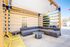 Chic outdoor patio area with a modern gray sectional sofa, vibrant yellow chairs, and a sleek round table under a stylish wooden pergola.