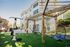 Charming courtyard with modern outdoor gym equipment and stylish hanging chairs, set against a picturesque apartment building backdrop.